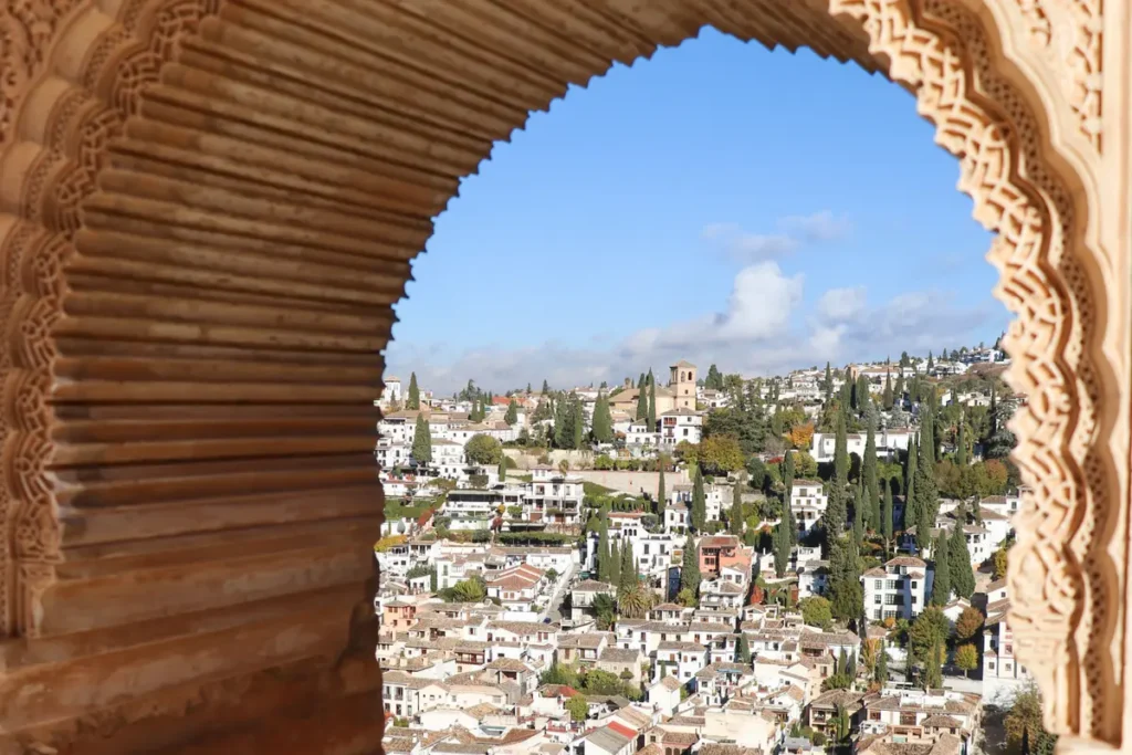 The Albaicin quarter framed by a carved horseshoe window in the Alhambra