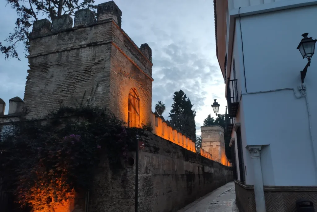 The walls of the Alcazar lit at dusk above a narrow street in Seville