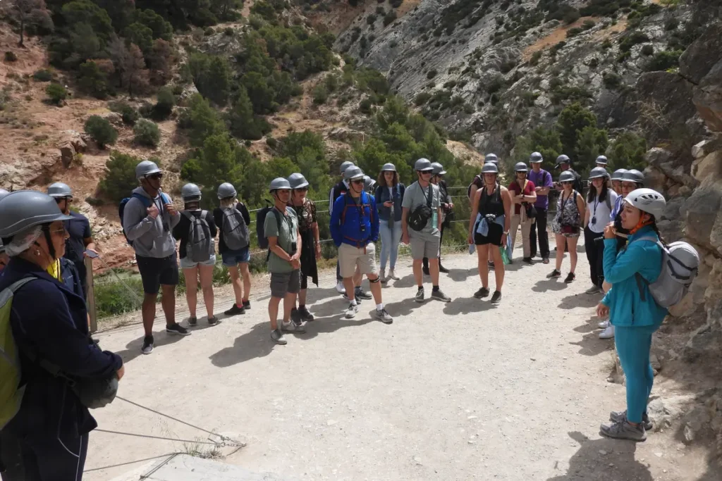 Walkers in helmets pausing on the Caminito del Rey with the gorge behind