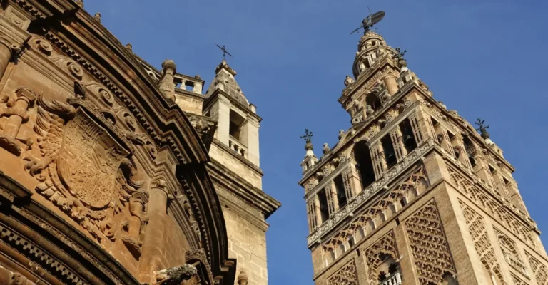 The Cathedral of Seville and the Giralda seen from below against a blue sky