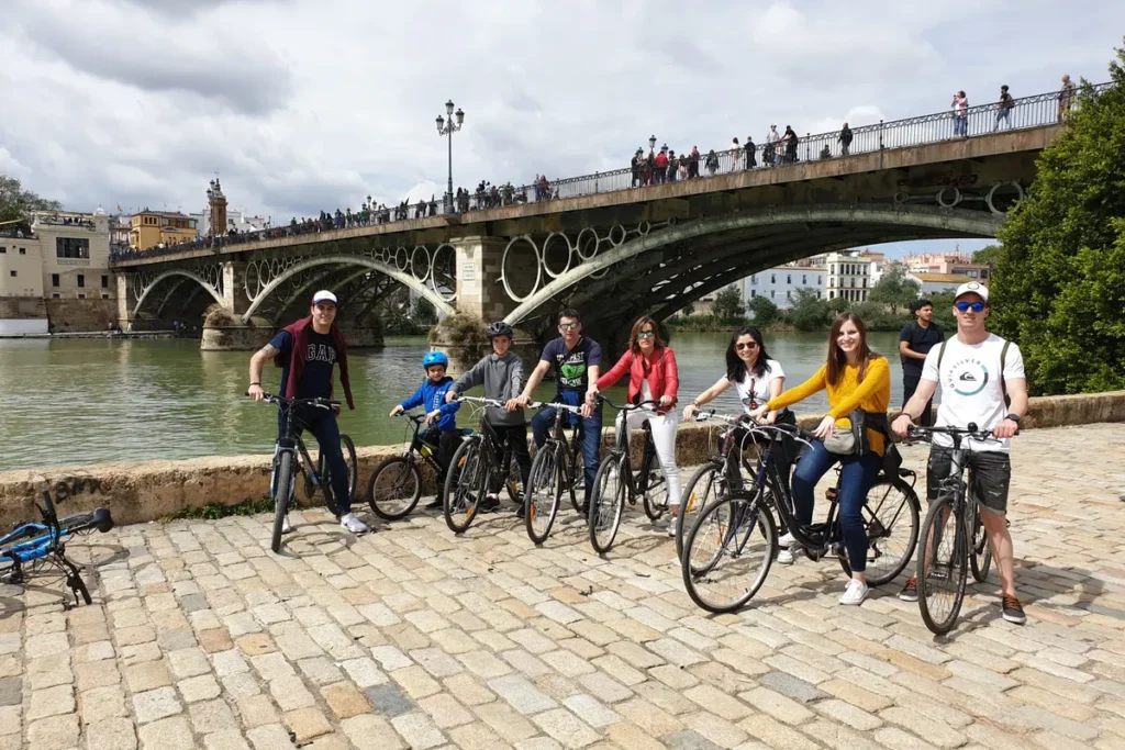 Cyclists stopped beside the Triana bridge on the riverside path