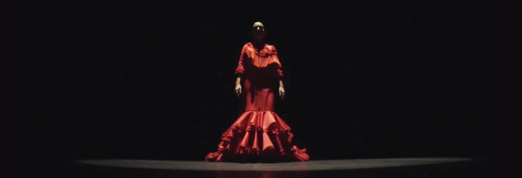 A flamenco dancer alone in a pool of light on a dark stage in Seville