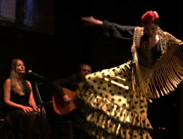 A flamenco dancer in a gold dress on stage in Seville