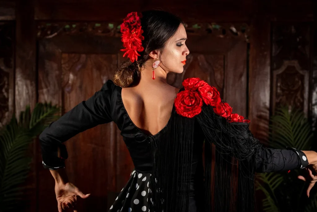 A flamenco dancer in a black dress with red flowers in her hair at a tablao in Triana, Seville