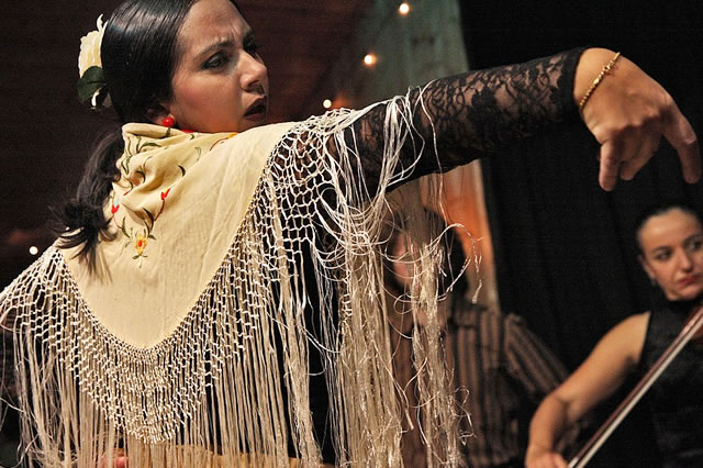 A flamenco dancer with a fringed shawl performing in a theatre in Seville