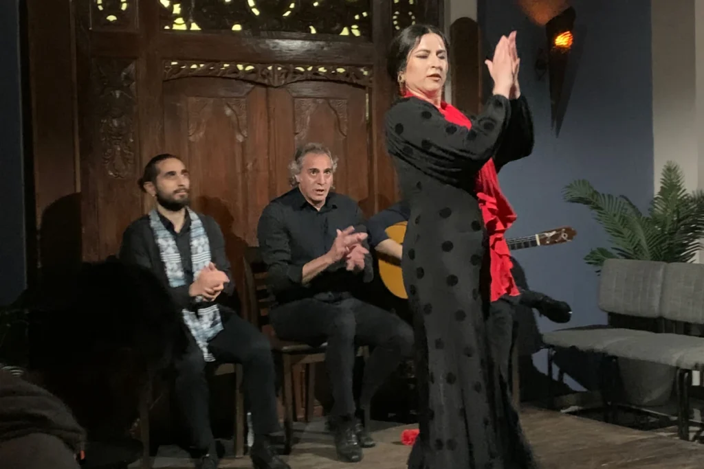 A flamenco dancer clapping beside the singer and guitarist during a show in Triana