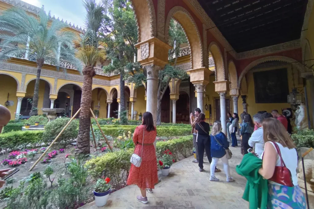 Visitors walking in the garden courtyard of the Palacio de las Duenas in Seville