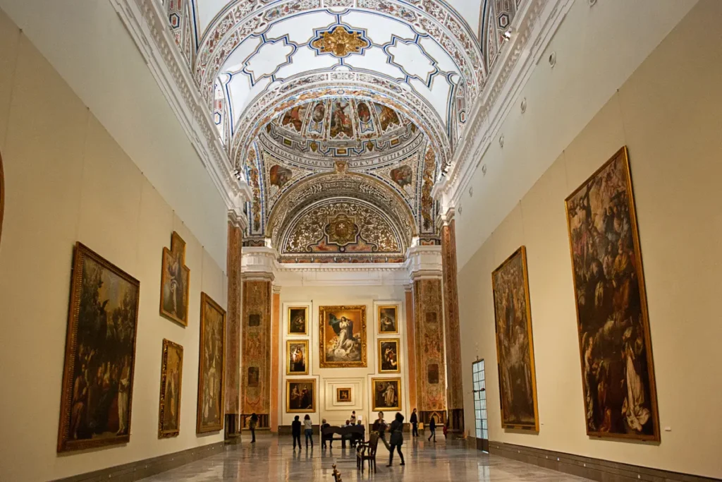 The vaulted former church hall of the Museum of Fine Arts in Seville, hung with paintings