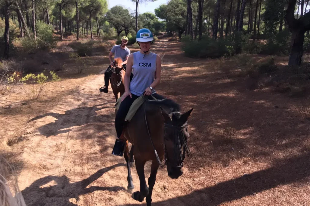 Riders following a sandy track through pine woods outside Seville
