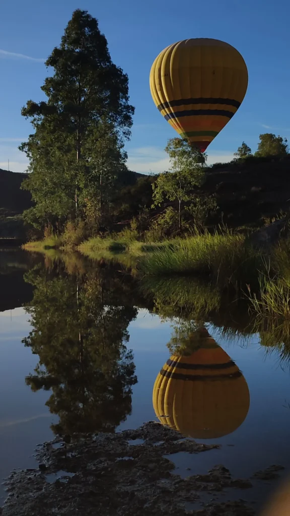 A hot air balloon reflected in still water at dawn near Seville