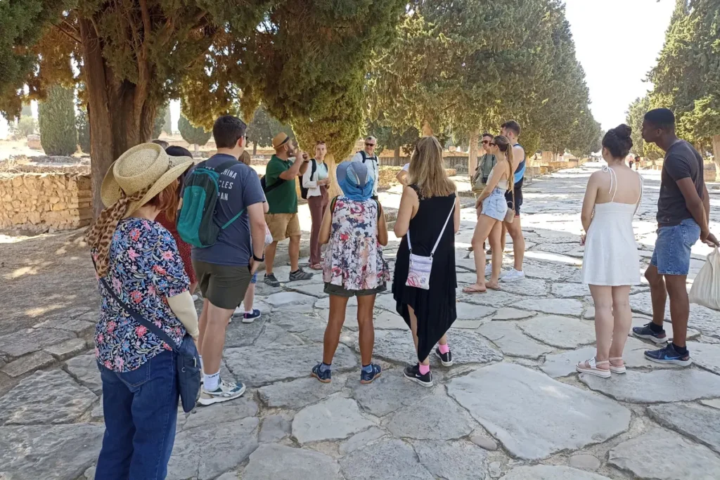 A guide explaining the Roman street plan to visitors at Italica