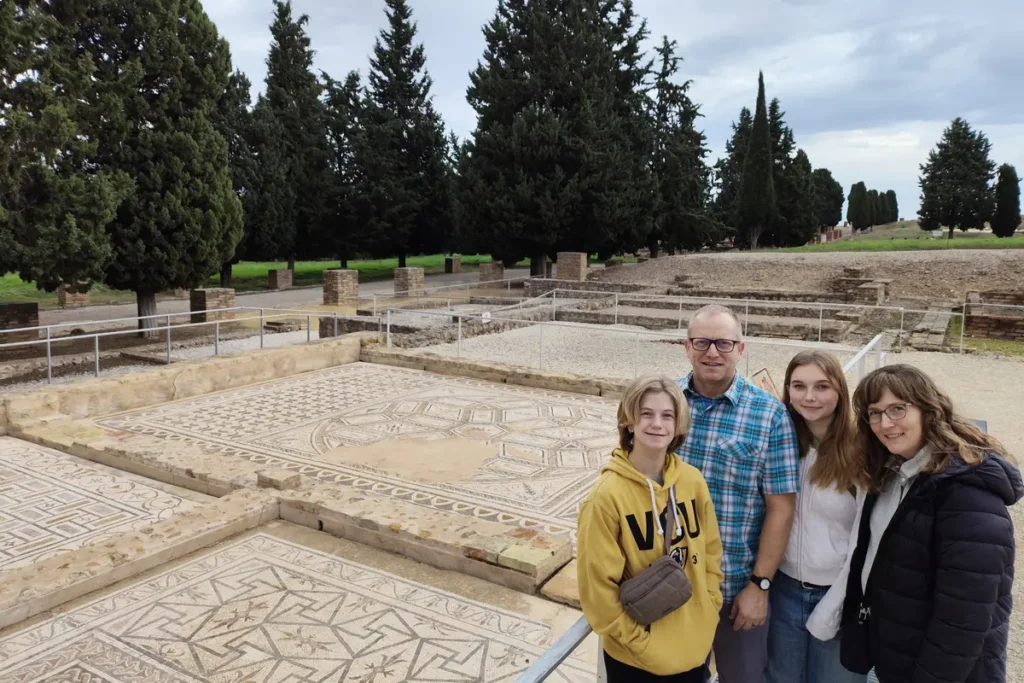 Visitors beside the mosaic floor of a Roman house at Italica