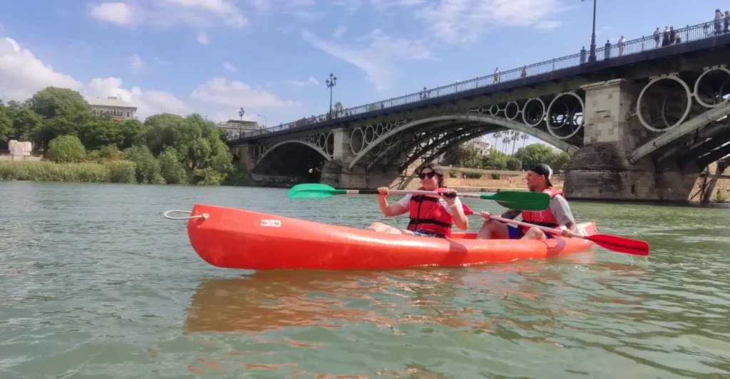Kayaks passing under the iron arches of the Triana bridge in Seville