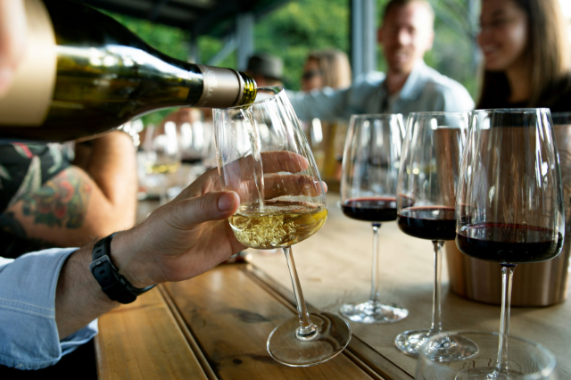White wine being poured at a tasting table with other glasses ready