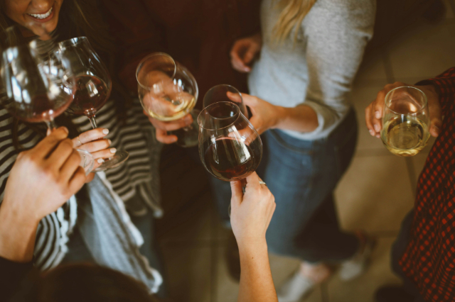 Hands raising glasses of red and white wine at a tasting