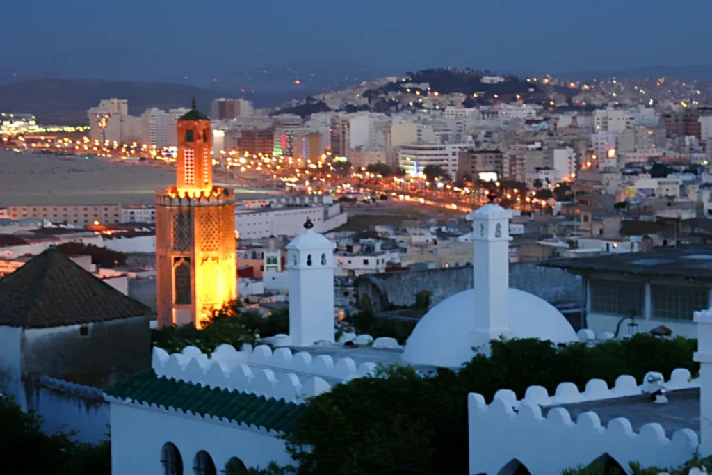 Tangier at dusk with a lit minaret above the bay