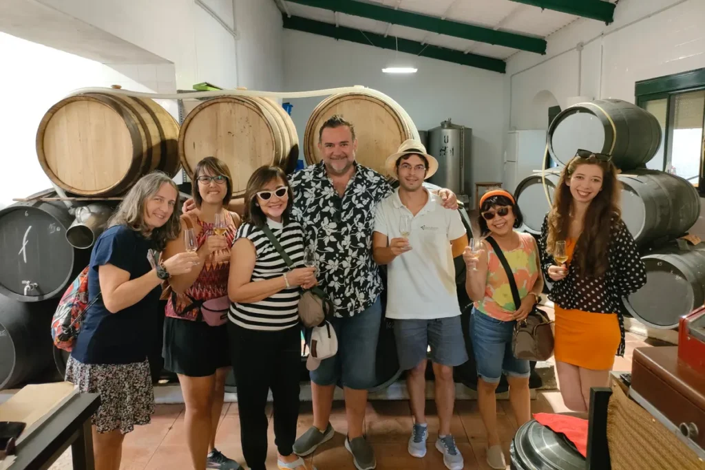 A group tasting wine in front of the stacked barrels of the ageing room
