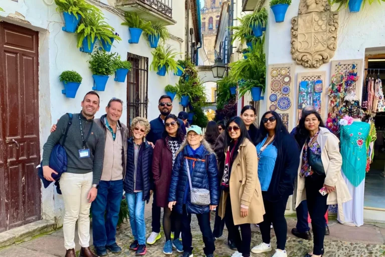 A group of travelers in a street lined with blue flowerpots