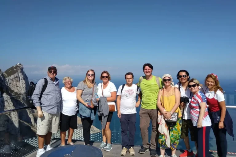 A group of travelers posing at a viewpoint over the sea