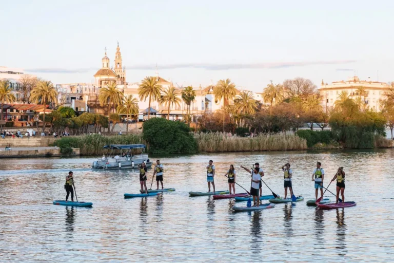 Travelers paddle surfing on the river with the Seville skyline behind