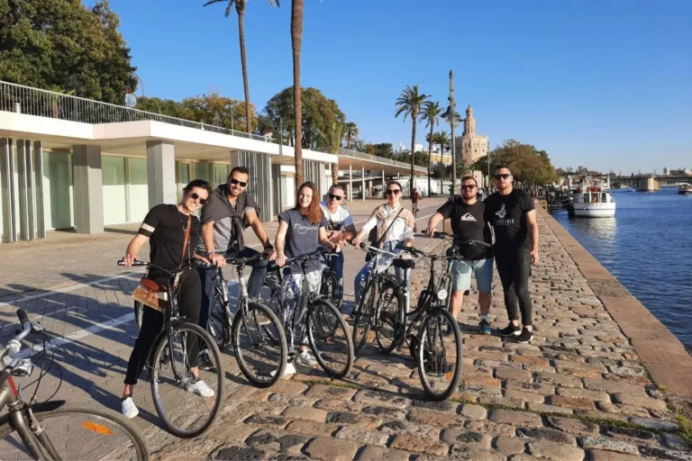 Travelers on a bike tour beside the Guadalquivir river in Seville
