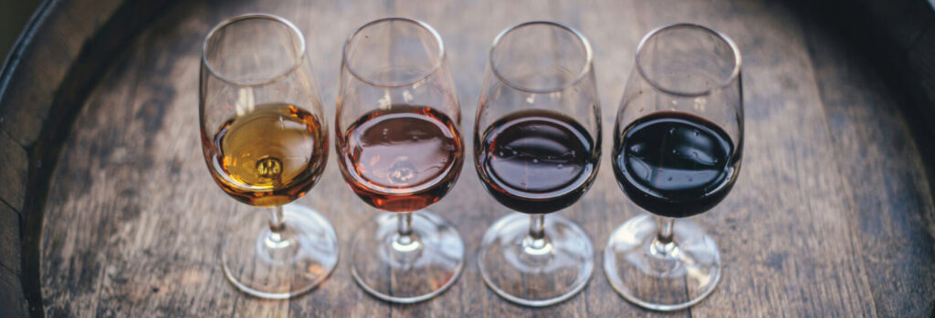Four glasses of wine lined up on a barrel for a tasting