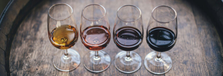 Four glasses of wine lined up on a barrel for a tasting